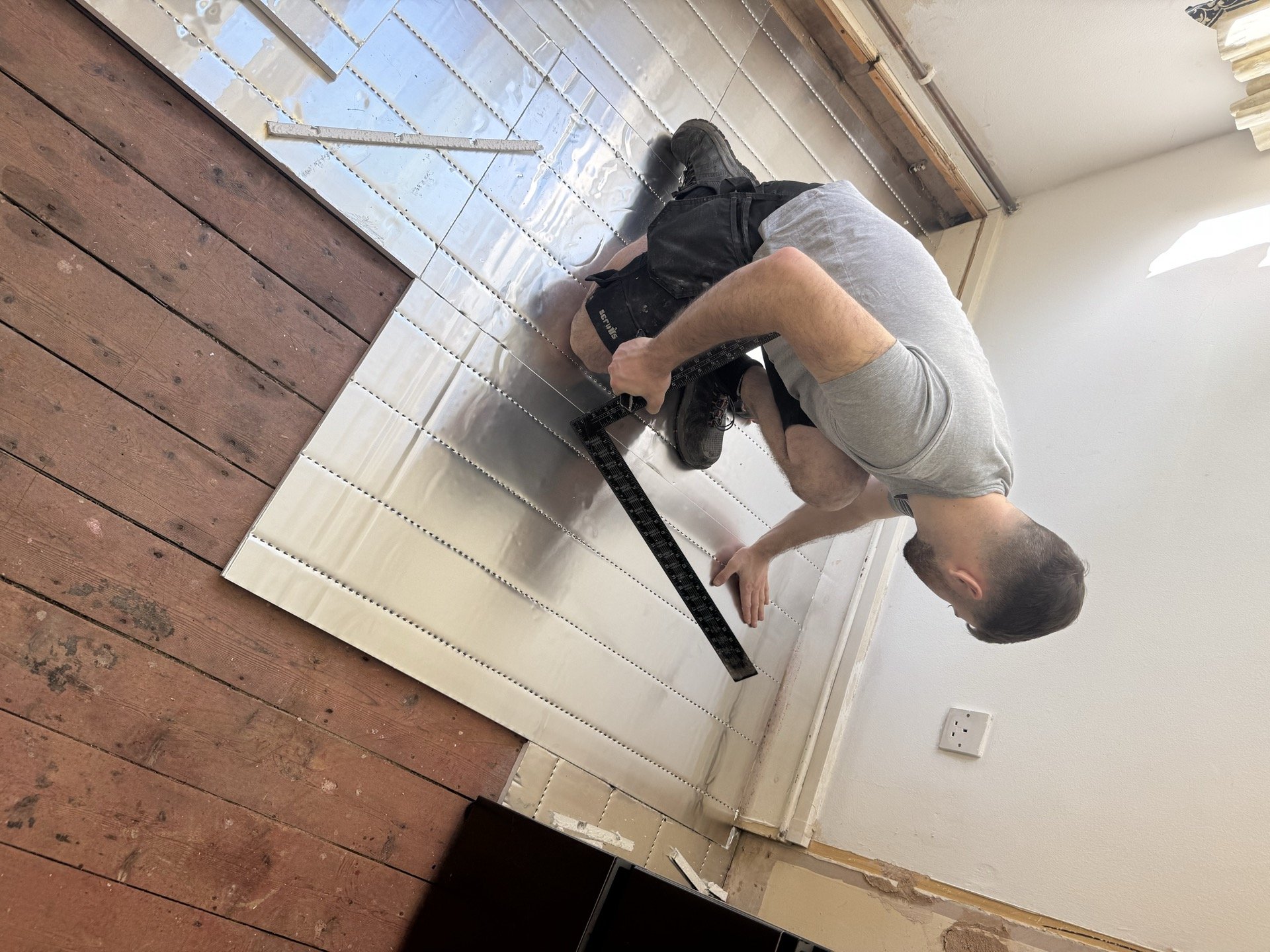 Jake clipping pipe channel into overlay panels over original timber boards