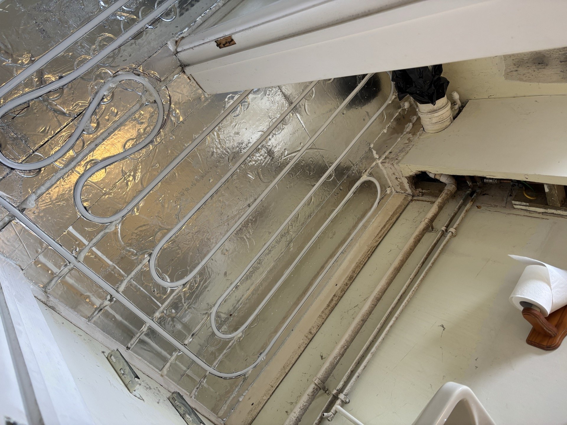 Retrofit underfloor heating routed around bathroom soil pipe