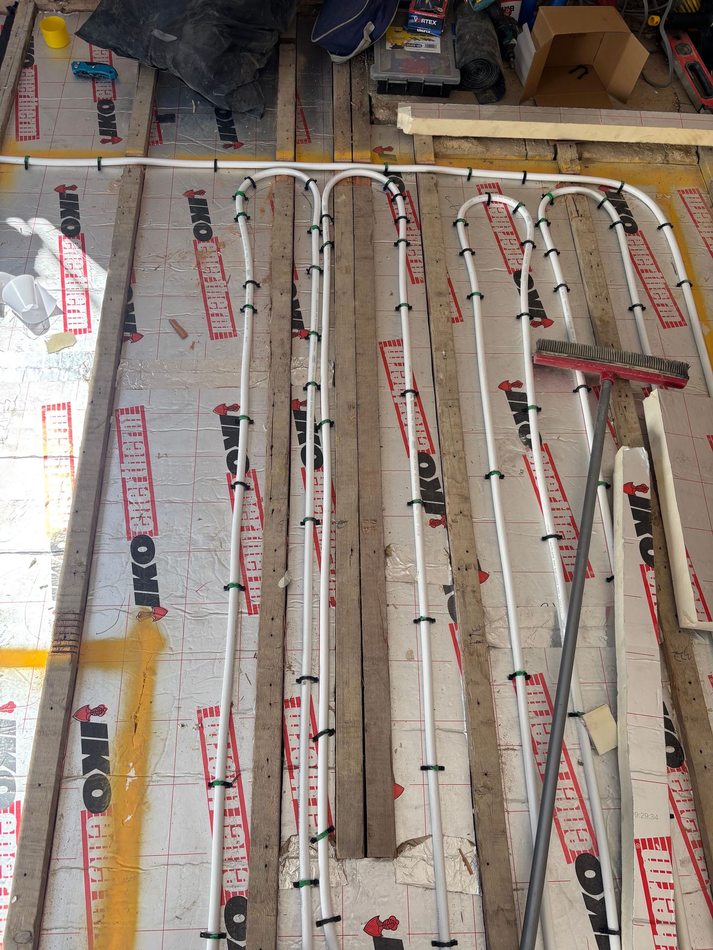Underfloor heating pipe routed down between floor joists